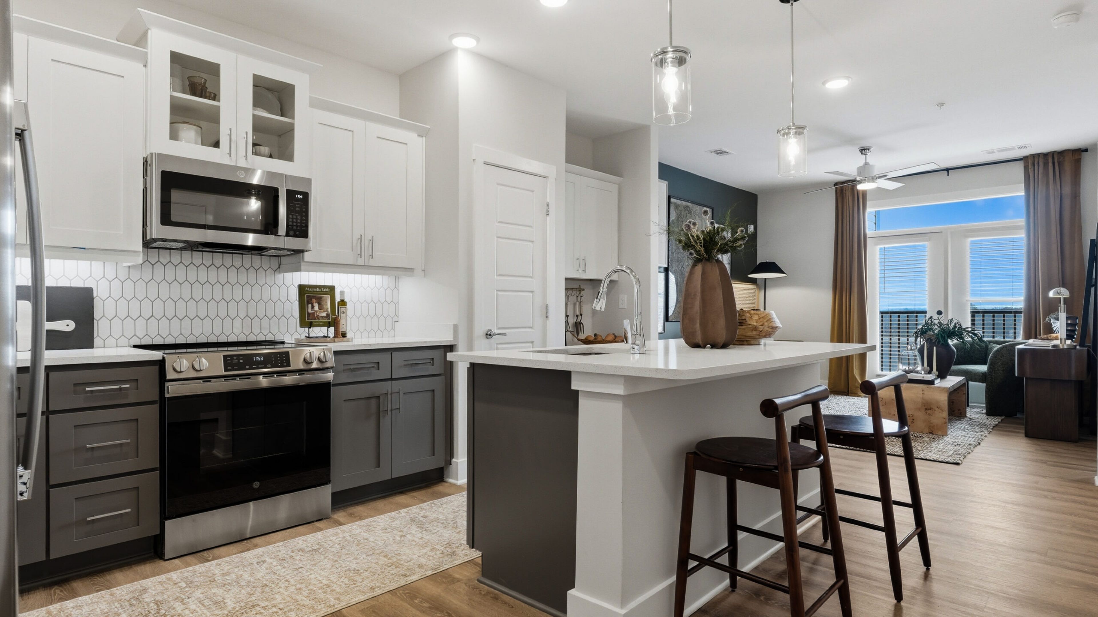 Hawthorne at Hixson apartment living space and kitchen with small dining table, kitchen peninsula, and stainless steel appliances