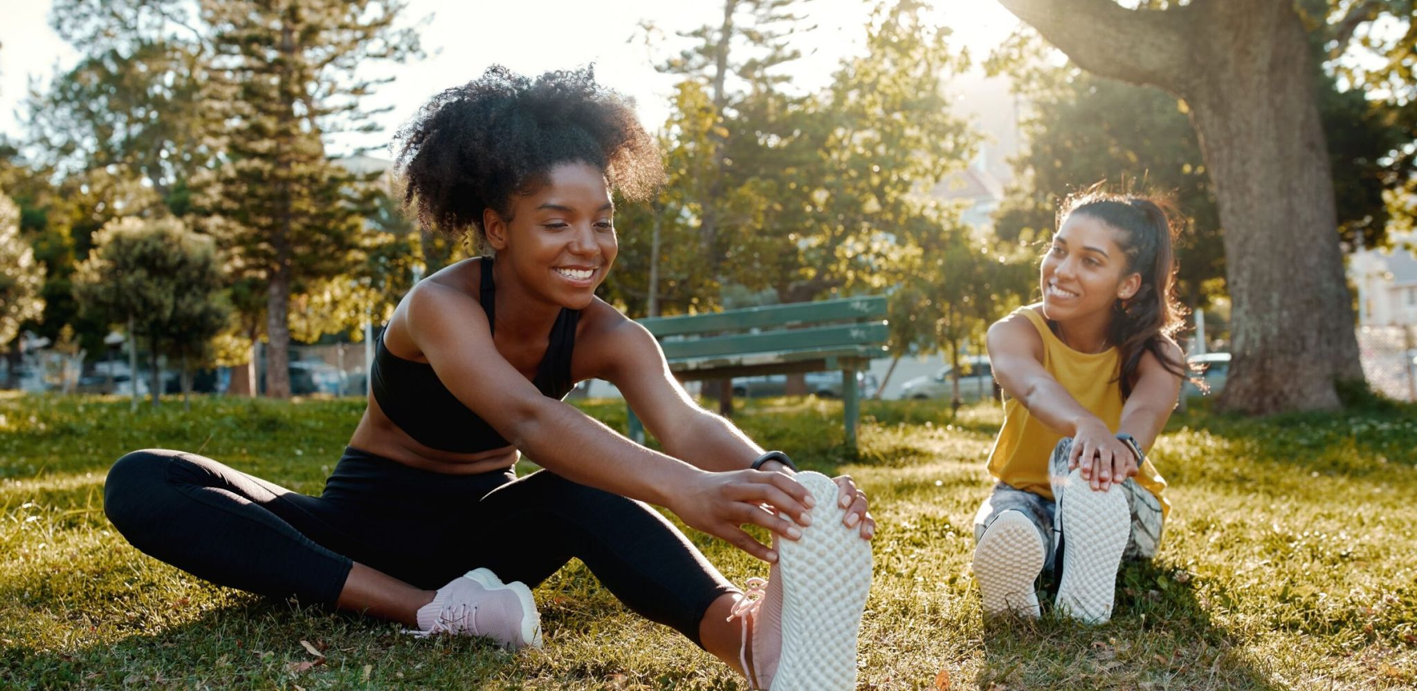 Hawthorne at Hixson female diverse friends doing stretching exercise in the park - diverse friends warming up before doing group exercise
